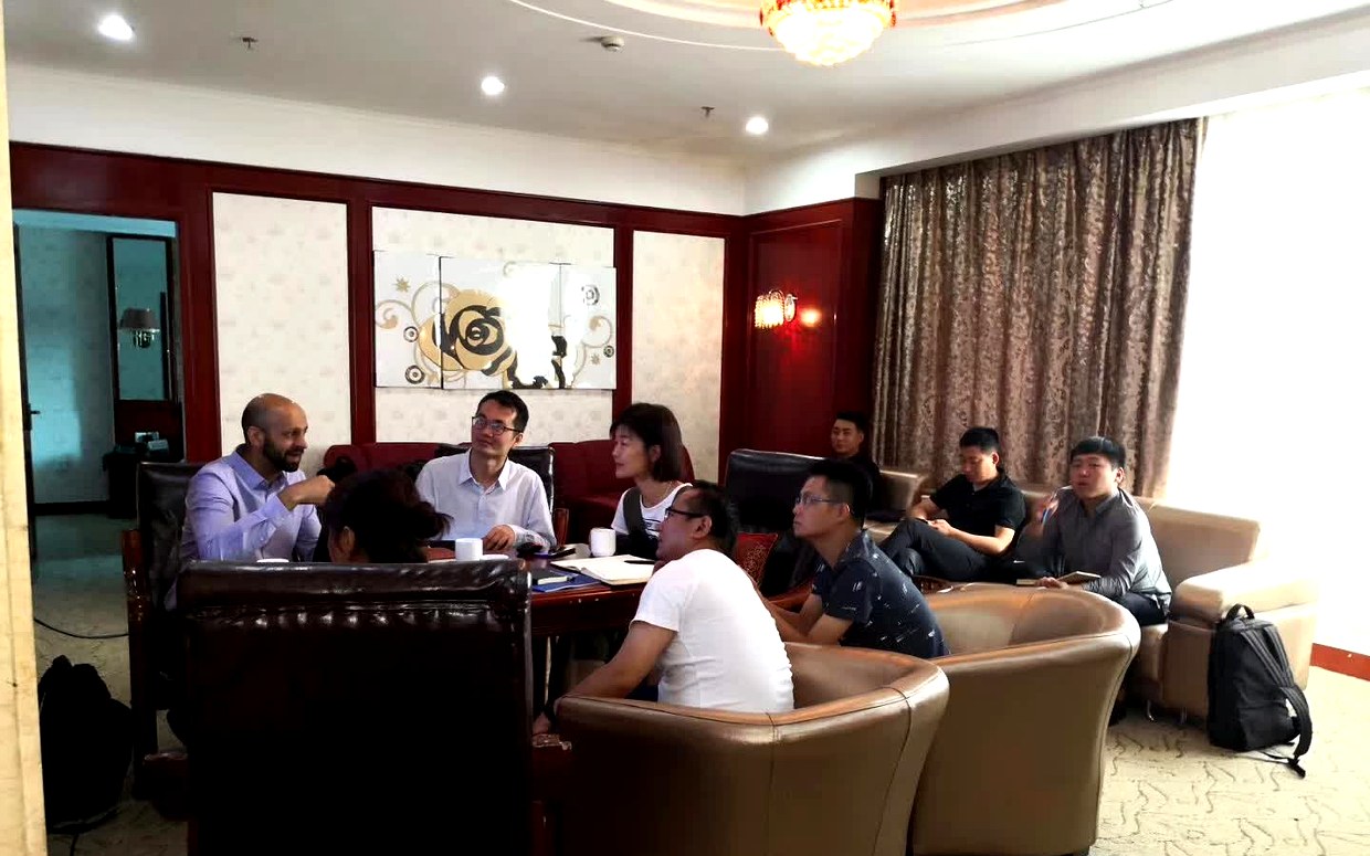 西北局工程院交流现场，双方人员围坐在沙发与茶几旁讨论