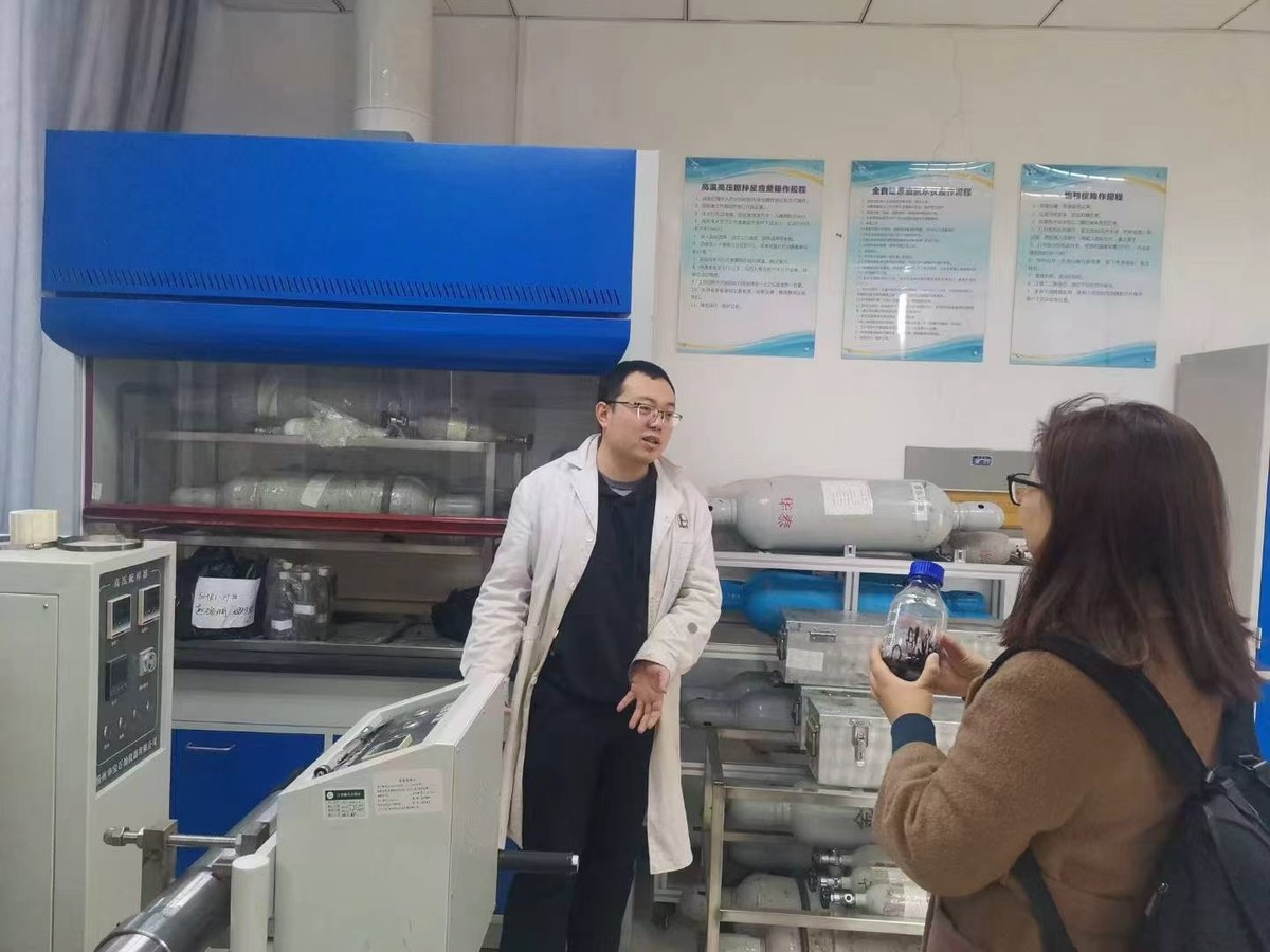 实验中心技术人员对照实验装置讲解样品前处理流程，与会者手持样品瓶