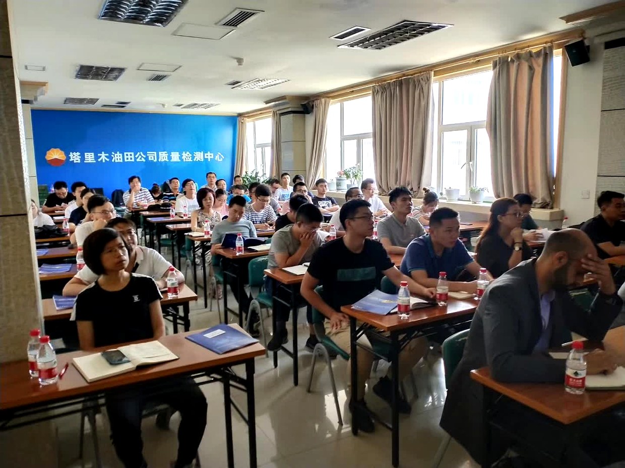 塔里木站交流现场，大教室内坐满参会人员，前方墙面有塔里木油田公司质量检测中心标识