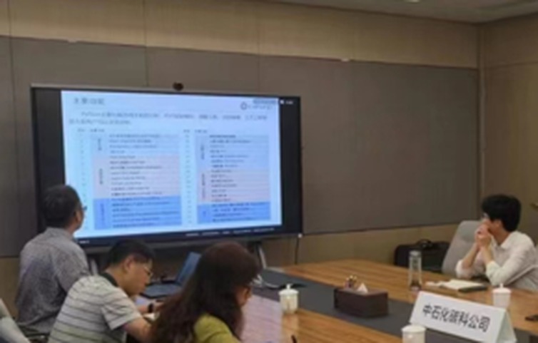 技术交流现场通过大屏演示技术资料，桌上摆放中石化碳科公司桌牌